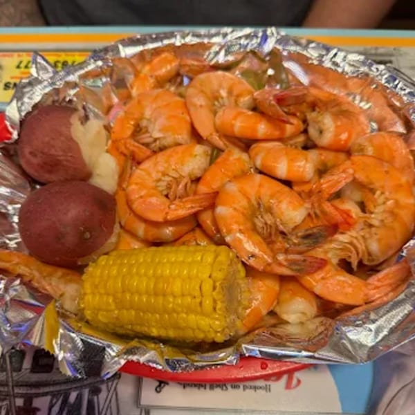 Cajun shrimp boil with red potatoes and corn on the cob in a foil-lined basket.