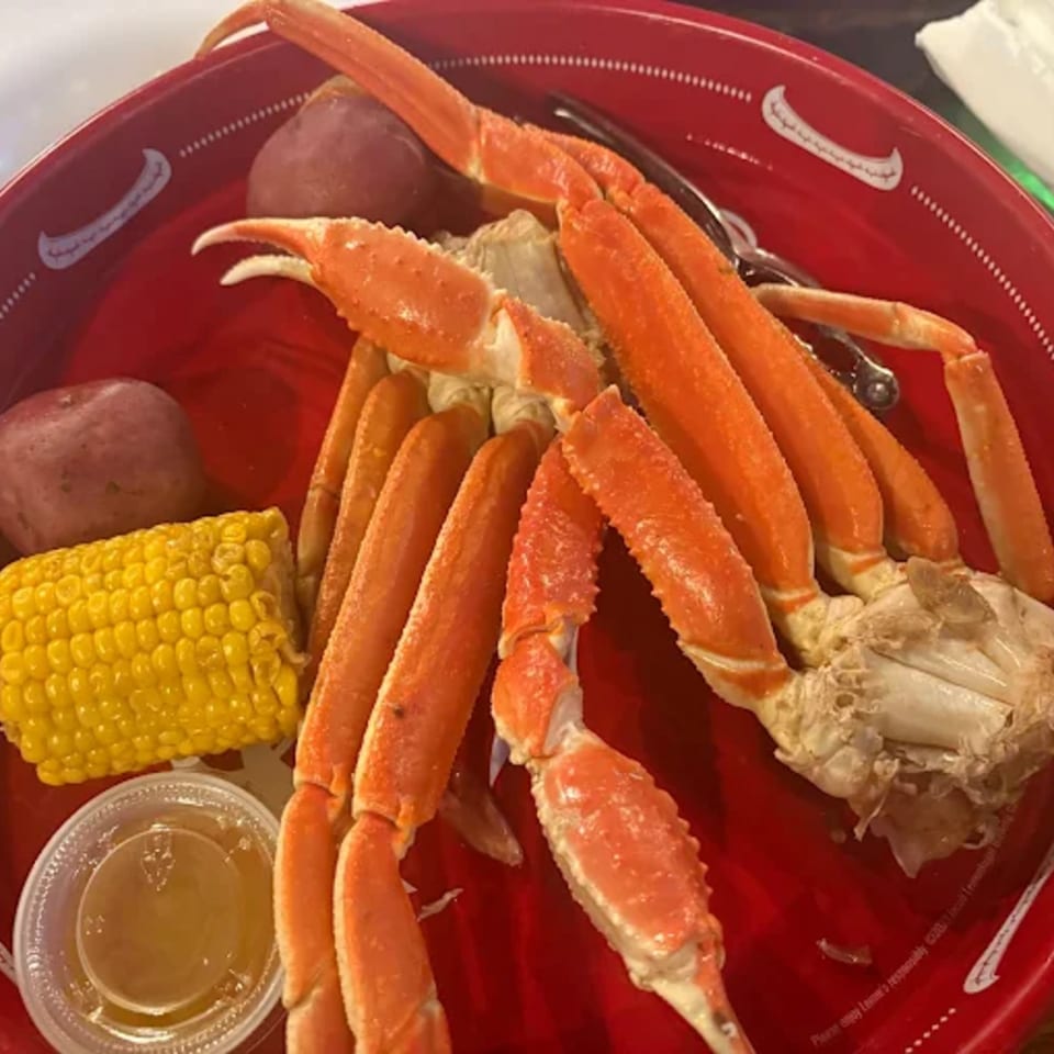 Cajun crab legs, corn on the cob, and potatoes on a red tray at Dat Cajun Place Cafe.